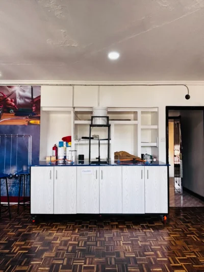 White island bench marked Chemistry with a blue worktop, a fire extinguisher and a raised water tank on a frame