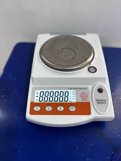 White electronic balance with a steel pan and a digital display on a blue bench