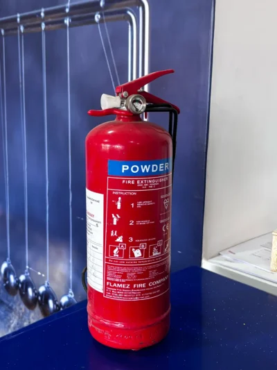 Red 2 kg dry powder fire extinguisher standing on a blue bench