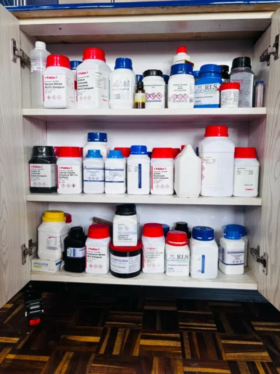 Cabinet with three shelves of labelled reagent bottles, including barium nitrate, sodium carbonate and potassium nitrate