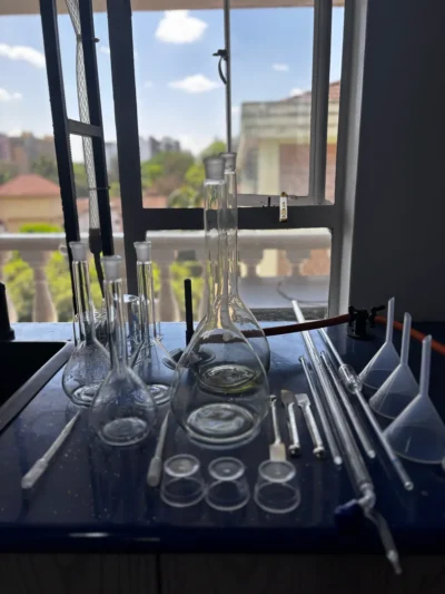 Volumetric flasks, filter funnels, glass tubes, spatulas and watch glasses on a bench in front of a window